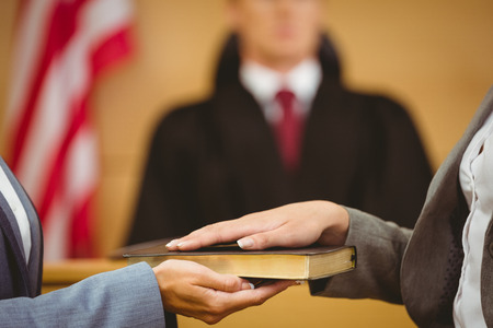 witness swearing on the bible telling the truth in the court room